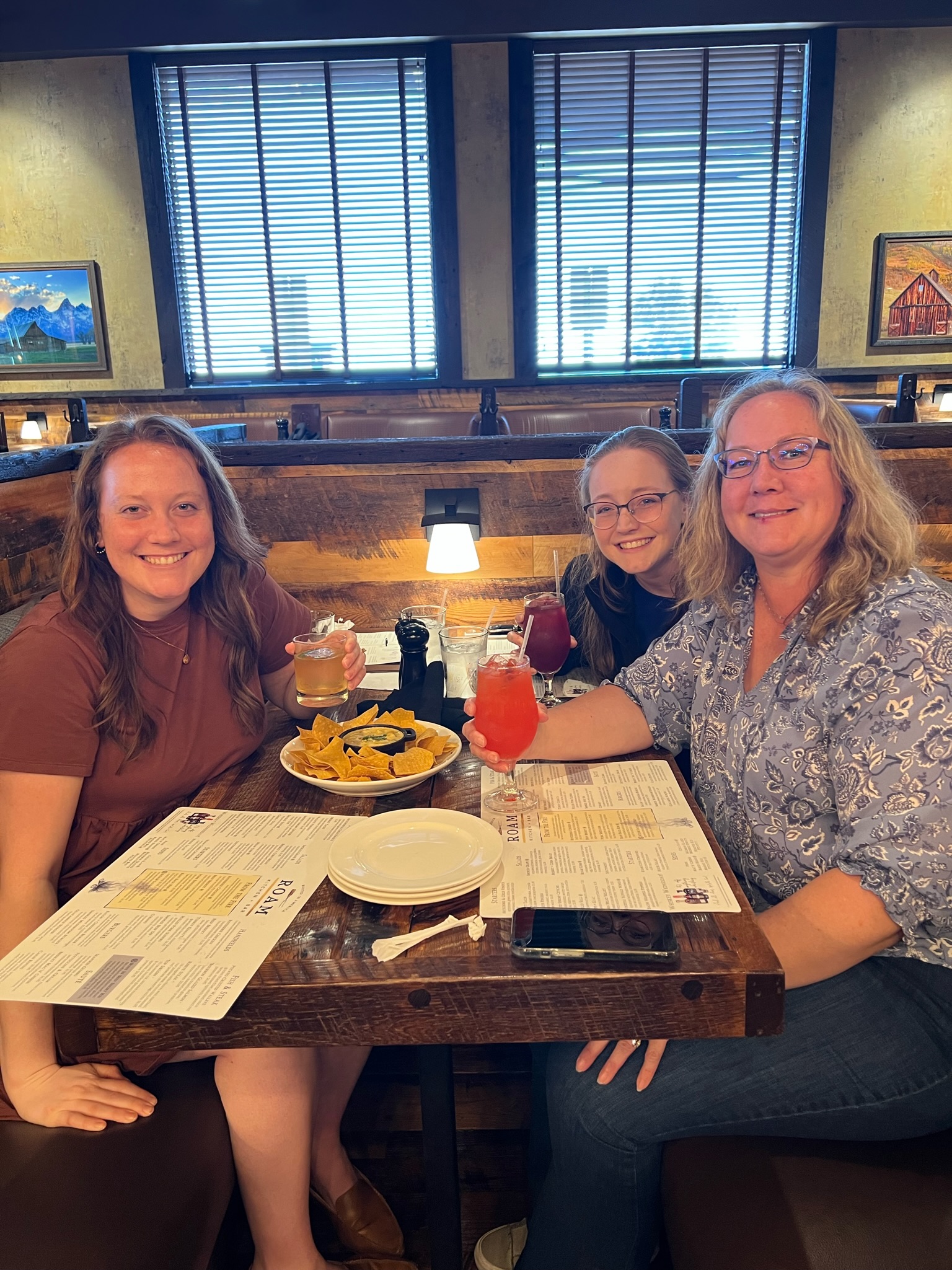 MOther and two daughters sitting in booth with drinks and menus.